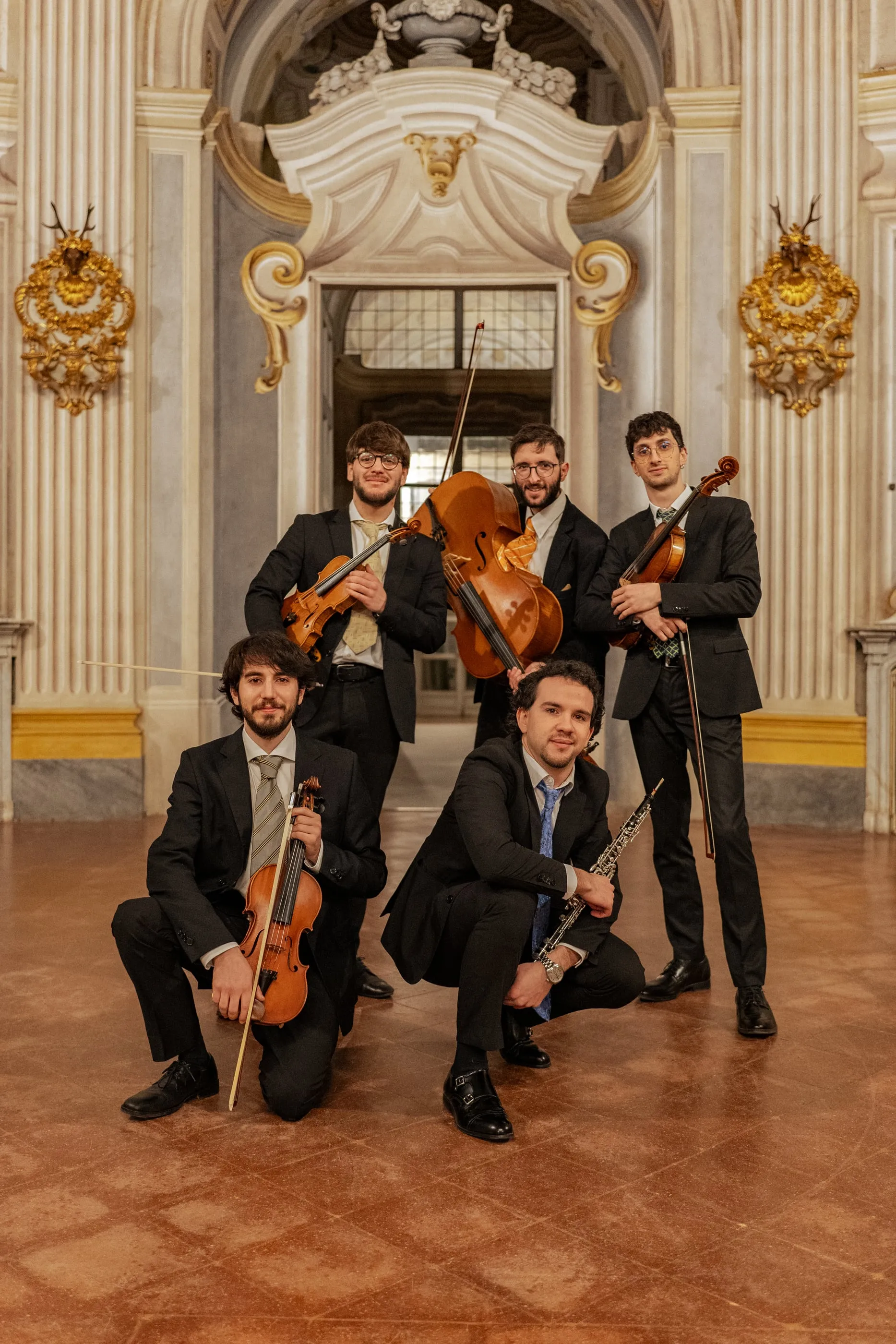 Ritratto di gruppo dell'Ensemble Belliners con archi e oboe nella sala barocca di Stupinigi